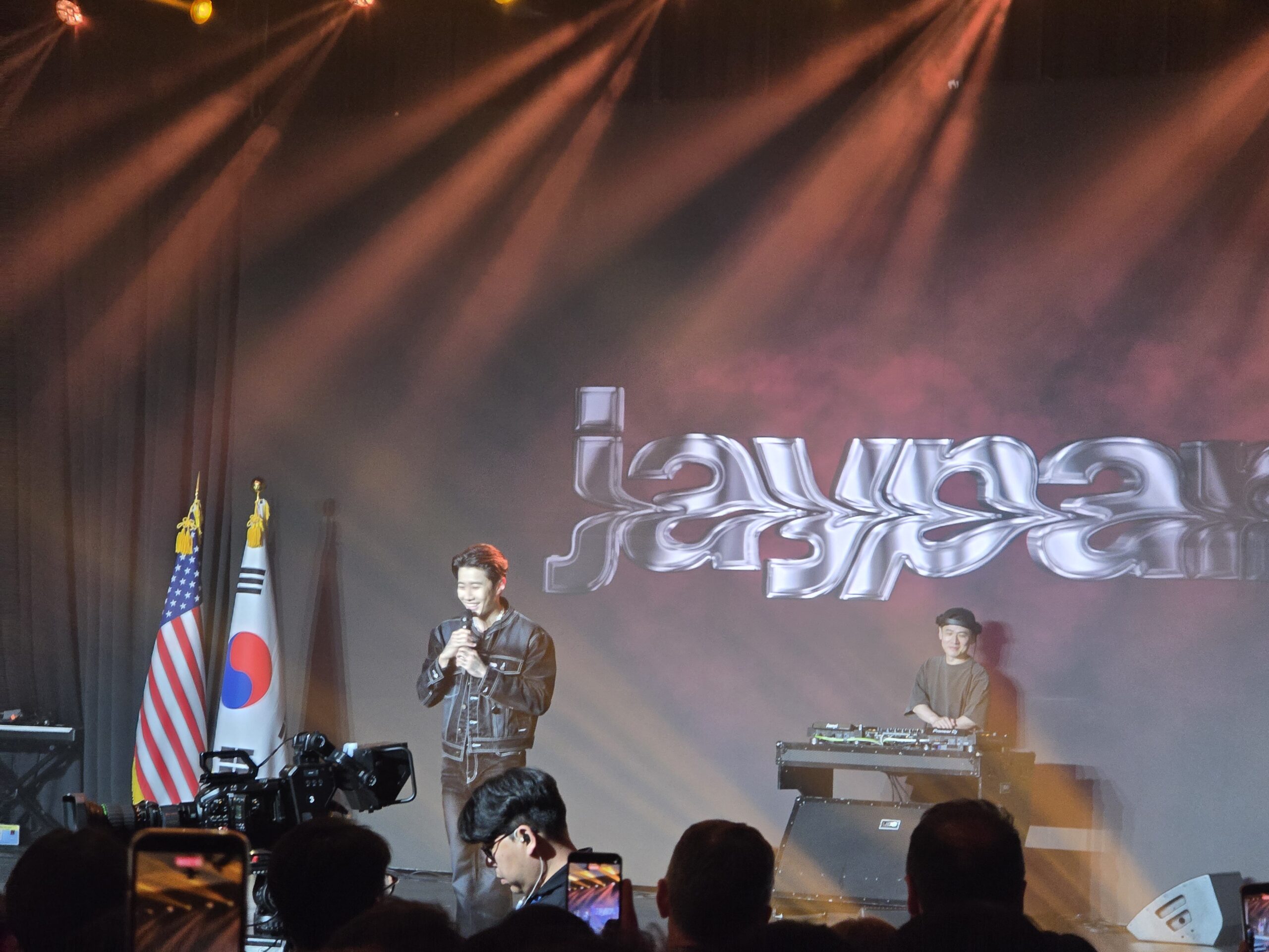 Jay Park performing on stage at the U.S. Embassy Fourth of July Reception in Seoul, with the U.S. and South Korean flags beside the stage.