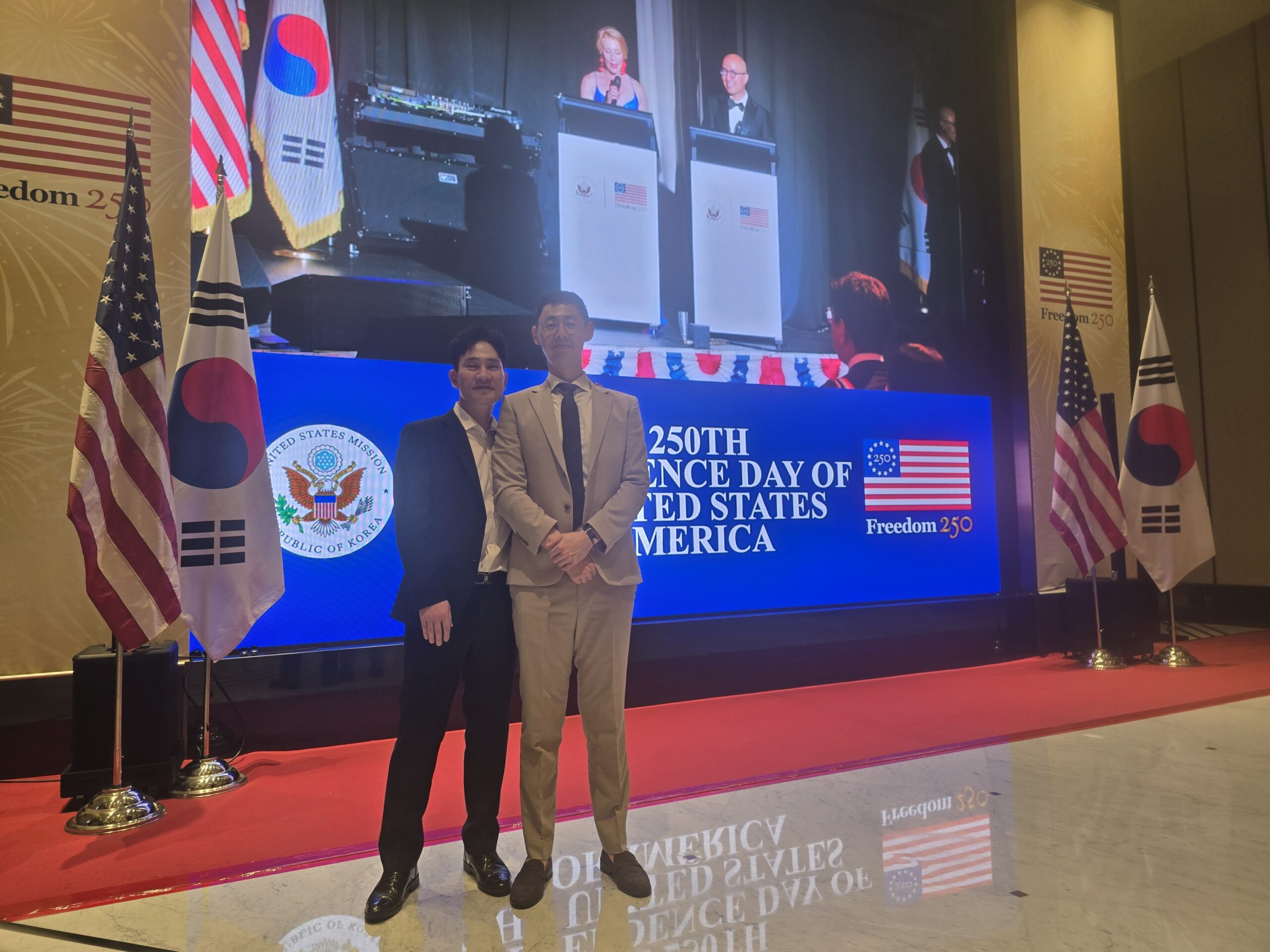Attorneys Won Sang Kang and Hyun Don Shin of Kang & Shin standing in front of the stage at the U.S. Embassy Fourth of July Reception in Seoul.